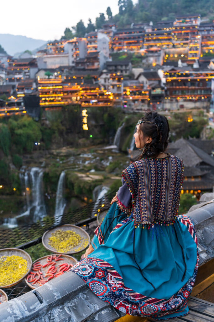 Mujer en vestido tradicional mirando la ciudad de Lijiang